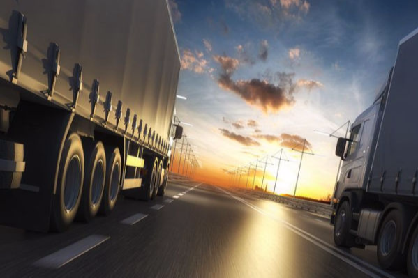 Trucks driving on highway at sunset